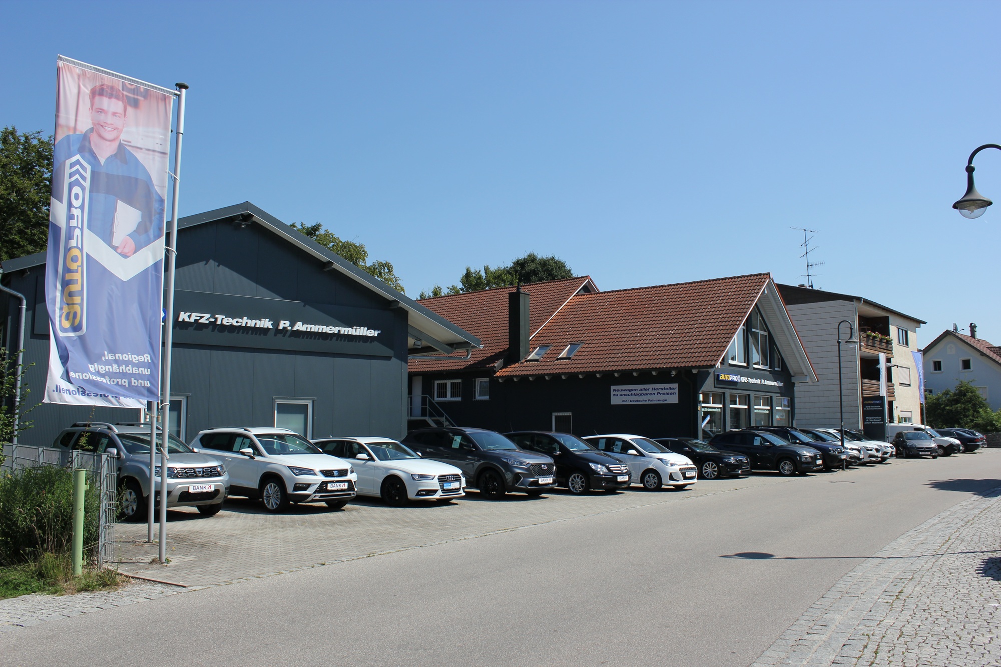 Zu sehen ist der Firmensitz von KFZ-Technik Ammermüller in Kirchham bei Passau. Autos diverser Modelle stehen vor dem Gebäude.